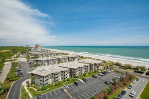 Un ensemble d’appartements situé sur la côte, composé de plusieurs bâtiments, avec un parking et une vue sur la plage.