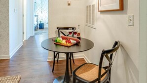 A dining area with a round table, two chairs, a hanging light fixture, and a framed picture on the wall. - Nashville - 1808 State St #208 (Nashville)