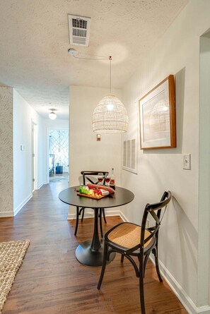 A dining area with a round table, two chairs, a hanging light fixture, and a framed picture on the wall. - Nashville - 1808 State St #208 (Nashville)