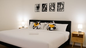 A neatly made bed with white bedding, two decorative pillows, and a bedside table with a lamp. - Kingbed, Resort Style Pool, Gym, Neartheheights (Houston)