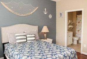 A bedroom with a bed, a nightstand, a lamp, and a view of the bathroom. - Heatherstone 1063 (Myrtle Beach)