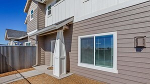 A residential building with a covered patio, a window with blinds, and a small outdoor utility box. - Bliss Flagstaff 49 (Flagstaff)