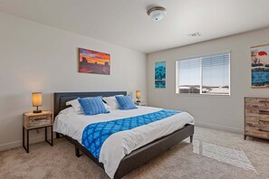 A bedroom with a bed, two bedside tables with lamps, a window with blinds, and artwork on the walls. - Bliss Flagstaff 49 (Flagstaff)