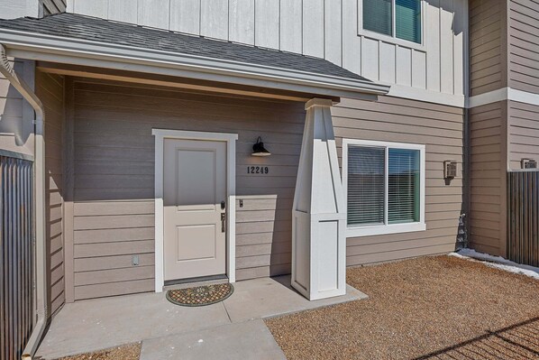 A two-story building with a front door, a mailbox, and a window with blinds.