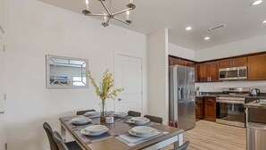 A modern kitchen with stainless steel appliances, a dining area with a table set for four, and a mirror on the wall. - Bliss Flagstaff 49 (Flagstaff)