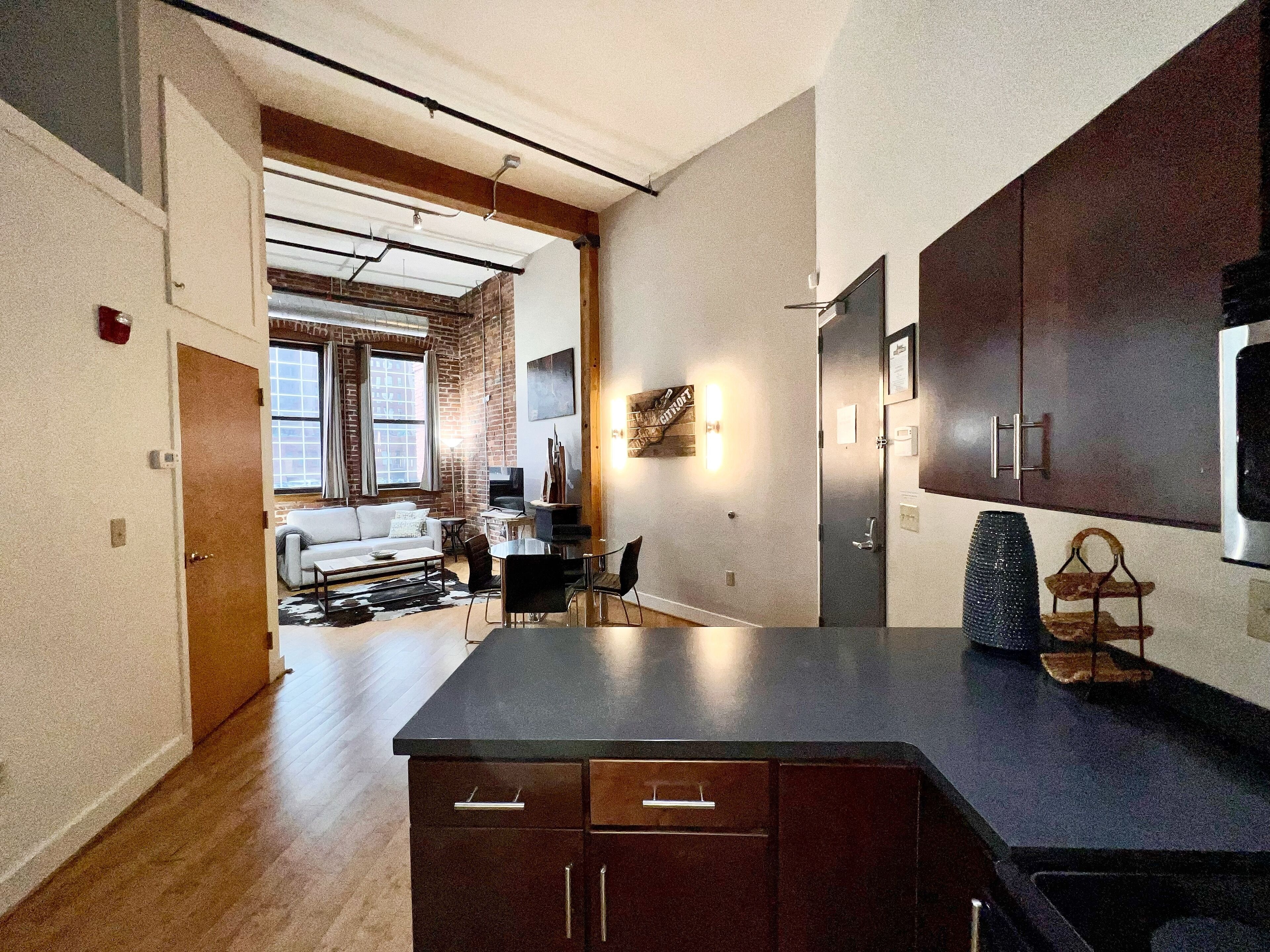 Una cocina moderna con armarios oscuros, una isla grande y una zona de comedor con mesa y sillas.