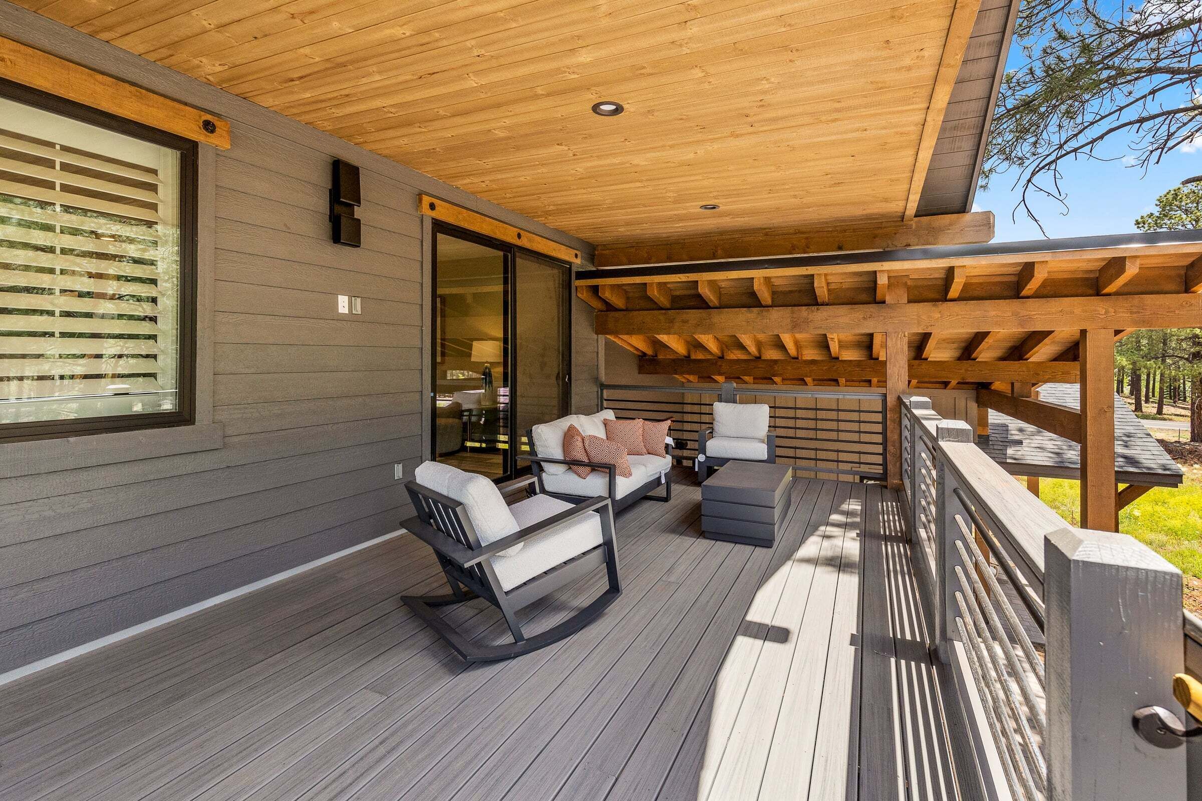 A covered outdoor seating area with wooden flooring and furniture.