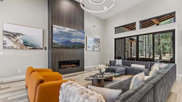 A modern living room with a fireplace, large windows, and artwork on the walls.