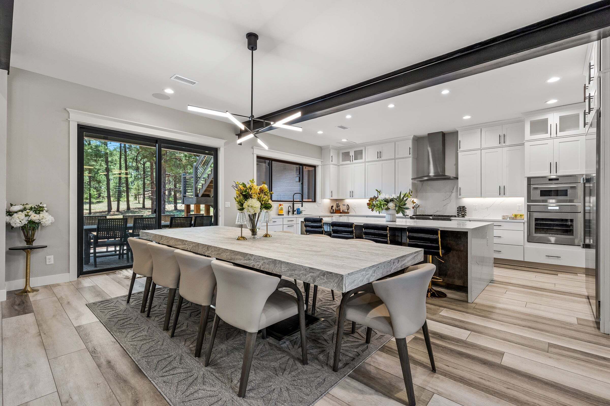 A modern kitchen with white cabinets, a large island, and a dining area with chairs.