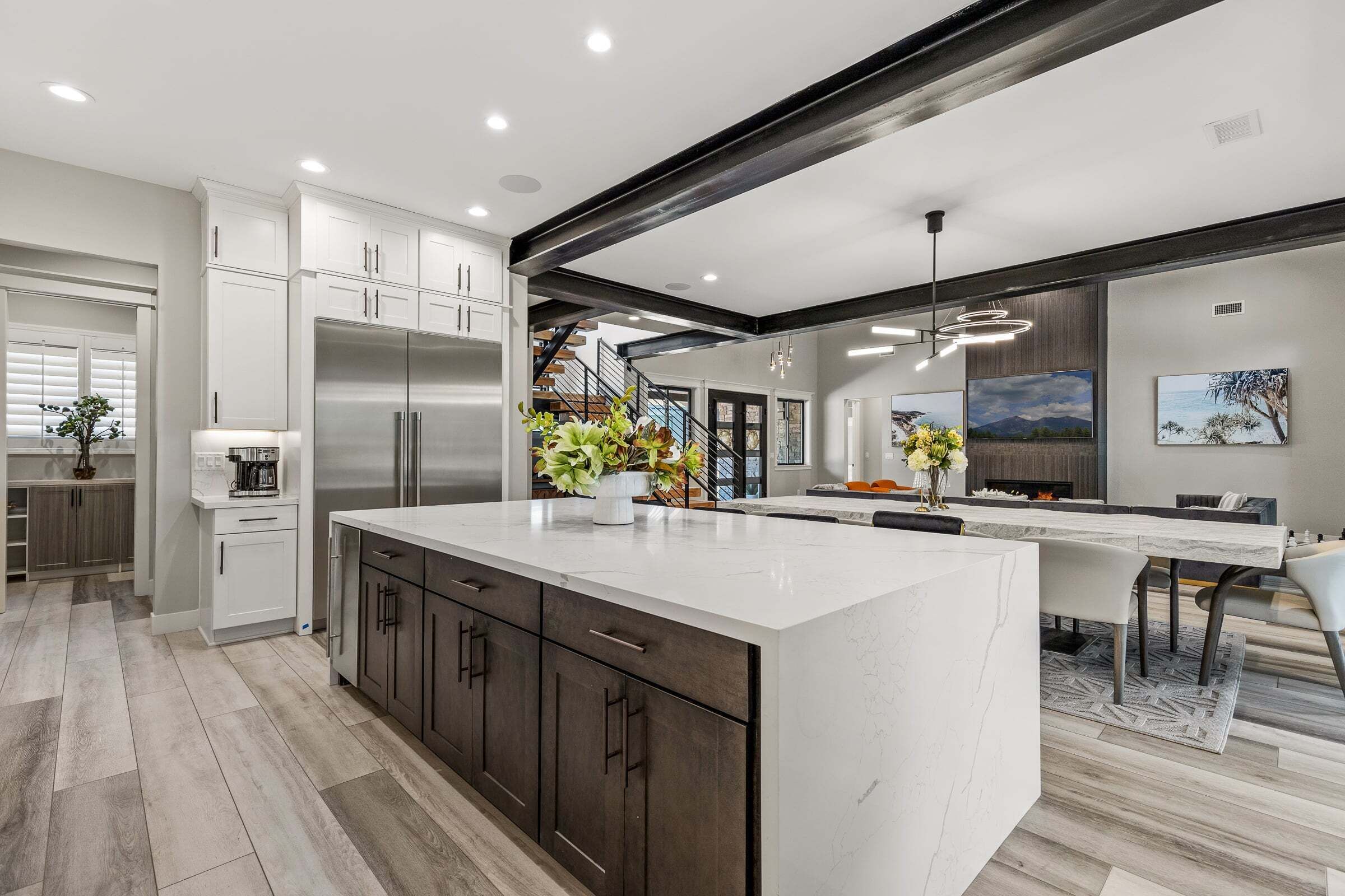 A modern kitchen with a large island, stainless steel appliances, and a staircase leading to an upper level.