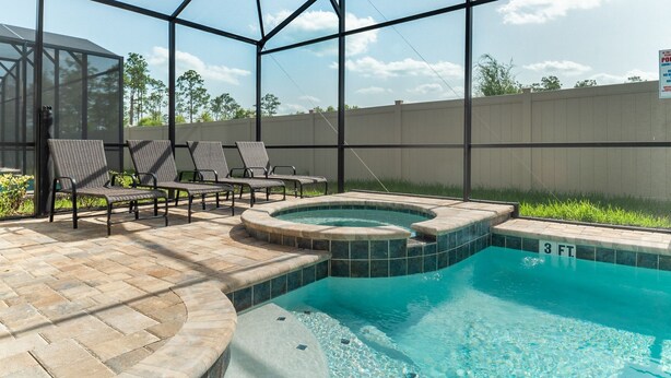 Piscina con hidromasaje, rodeada de sillones de descanso y una zona cubierta con pared de vidrio.