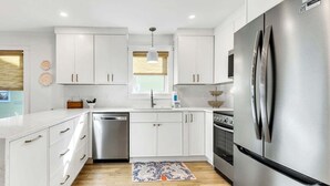 A modern kitchen with white cabinetry, stainless steel appliances, and a wooden floor. - Little Wing (Santa Rosa Beach)