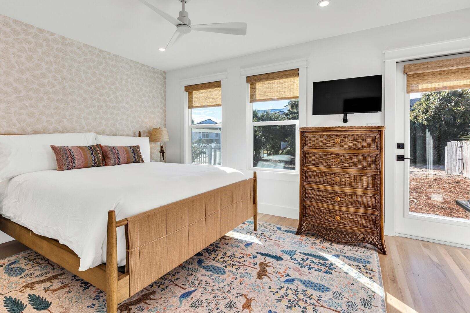 A bedroom with a bed, a television, a window, and a door.