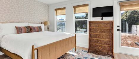 A bedroom with a bed, a television, a window, and a door.