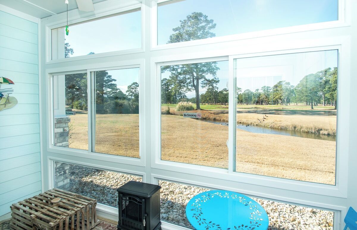 A room with large windows overlooking a grassy area with a pond and trees.