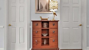 A wooden chest of drawers with a decorative lamp, a framed picture, and a small dog figurine on top. - Magnolia Pointe Luster Leaf 4825-102 (Myrtle Beach)