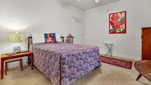A bedroom with a bed, a nightstand, a lamp, a ceiling fan, a door, and a wall-mounted picture. - Magnolia Pointe Luster Leaf 4825-102 (Myrtle Beach)