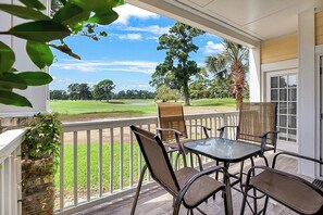 Überdachte Terrasse mit Blick auf einen Golfplatz.