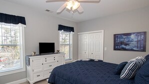 Un dormitorio con una cama grande, un aparador, un televisor y un cuadro en la pared.