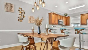 A modern kitchen with wooden cabinets, a central island, and bar stools. - Magnolia Pointe Magnolia Lake 4820-303 (Myrtle Beach)