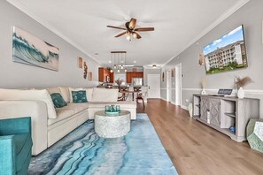 A modern living room with a sectional sofa, a coffee table, and a view into the kitchen. - Magnolia Pointe Magnolia Lake 4820-303 (Myrtle Beach)