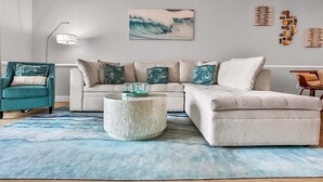 A modern living room with a beige sofa, teal armchair, and a round coffee table. - Magnolia Pointe Magnolia Lake 4820-303 (Myrtle Beach)