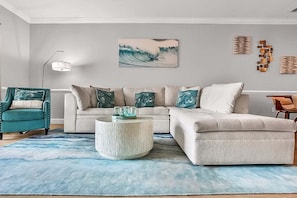 A living room with a sofa, armchair, coffee table, and artwork on the wall. - Magnolia Pointe Magnolia Lake 4820-303 (Myrtle Beach)