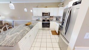 A modern kitchen with white cabinets, a stainless steel refrigerator, a microwave, and an oven. - Magnolia North 4839-204 (Myrtle Beach)