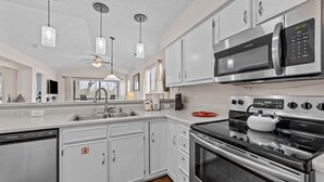 Una cocina moderna con electrodomésticos de acero inoxidable, muebles de cocina blancos e iluminación colgante.