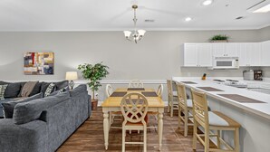 Een moderne keuken met witte kastjes, een centraal eiland en een eetgedeelte met een houten tafel en stoelen.