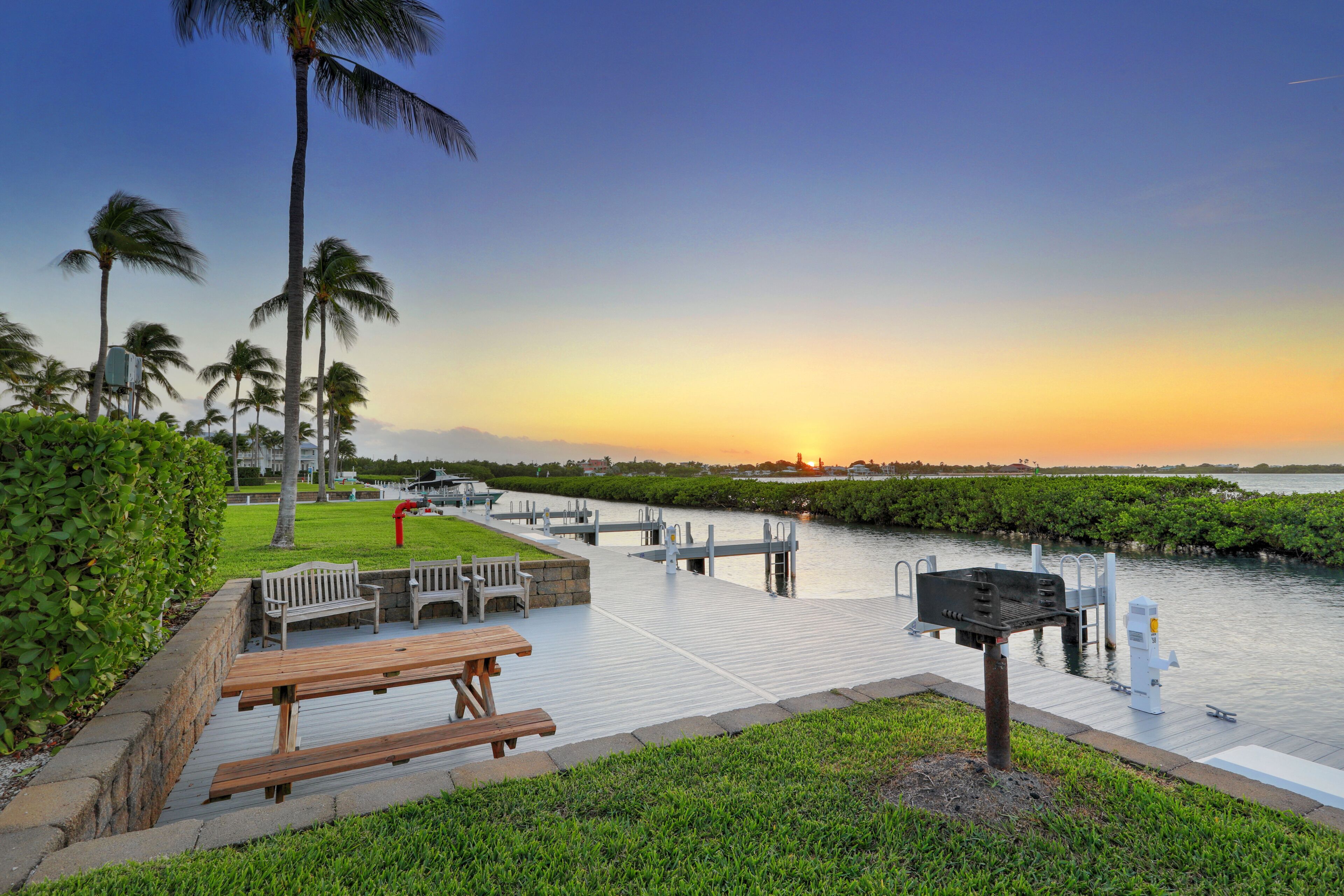 A waterfront park with a wooden deck, benches, and a fire hydrant.