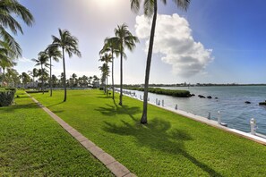 A grassy pathway with palm trees, a water body, and a distant shoreline. - Waterfront Luxury Villa With Sunset Views and Boat Slip (Marathon)