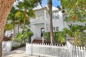 A two-story house with a white picket fence, palm trees, and a front porch. - Waterfront Luxury Villa With Sunset Views and Boat Slip (Marathon)