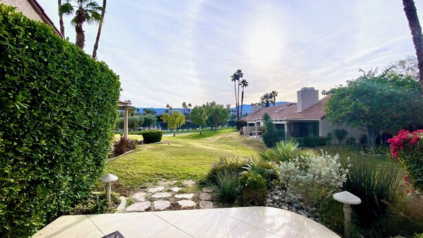 A well-maintained garden with a lawn, stone pathway, and various plants. - Modern Life (Rancho Mirage)