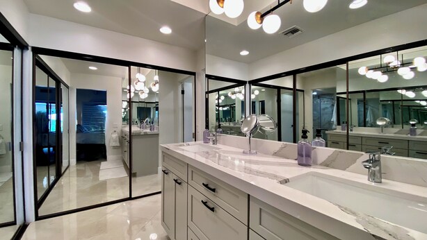 A modern bathroom with a large mirror, dual sinks, and a marble countertop. - Modern Life (Rancho Mirage)