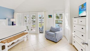 A bedroom with a bed, a nightstand, a dresser, a window with a view, and a door leading to a balcony. - Waterfront Luxury Villa With Sunset Views and Boat Slip (Marathon)