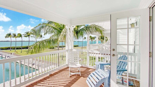 A covered outdoor area with a pool, white railings, and blue chairs. - Waterfront Luxury Villa With Sunset Views and Boat Slip (Marathon)