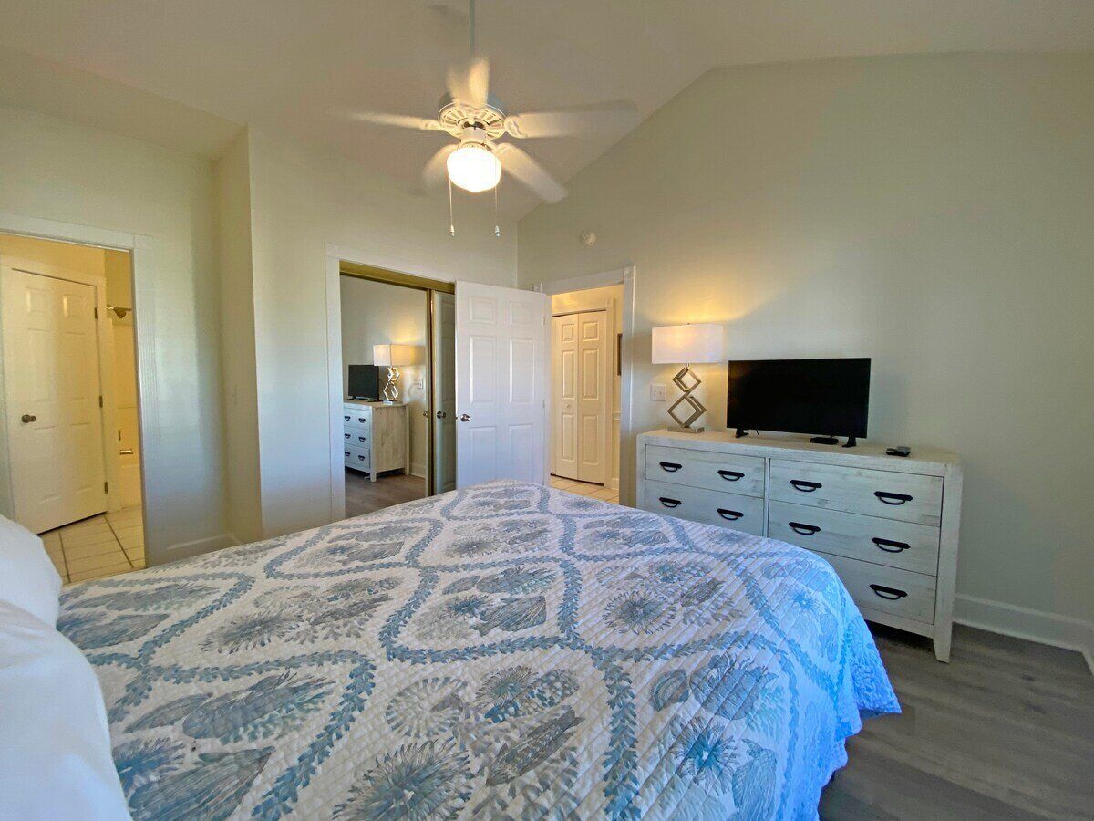 Makuuhuone, jossa on sänky, kattotuuletin, lipasto ja televisio.