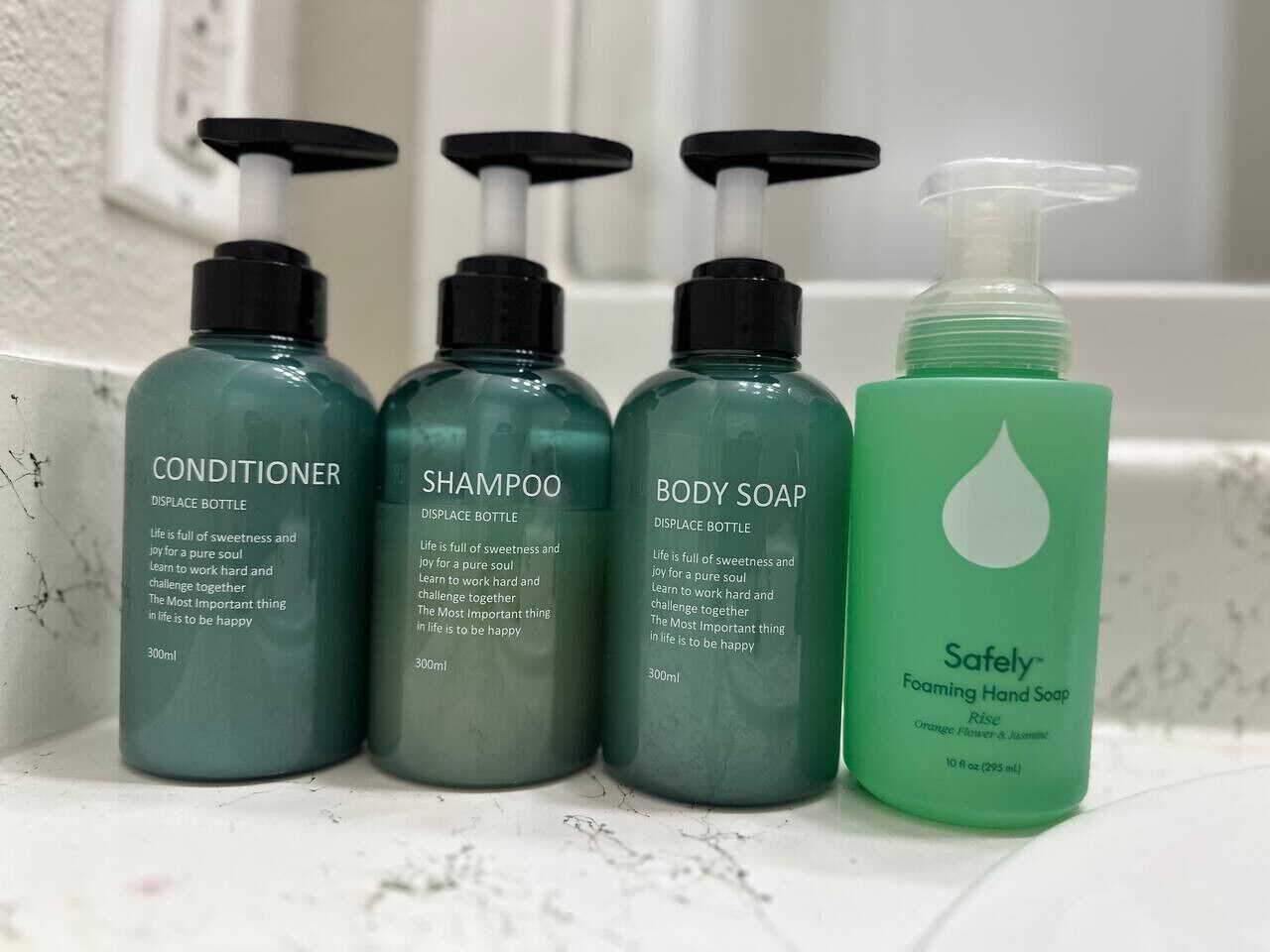 Four bottles of personal care products on a bathroom counter.