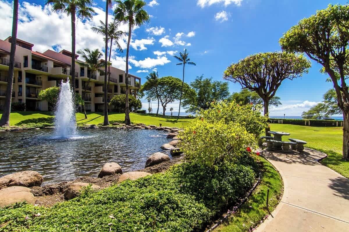 A hotel with a water feature, palm trees, and a well-maintained lawn.