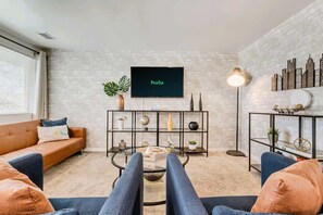 A living room with a sofa, coffee table, TV, and decorative items on shelves. - Convenient 2BR Apt w/ Parking, Near Downtown SLC (Salt Lake City)