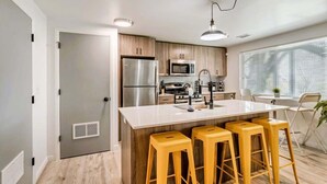 A modern kitchen with a central island, stainless steel appliances, and wooden cabinets. - Convenient 2BR Apt w/ Parking, Near Downtown SLC (Salt Lake City)