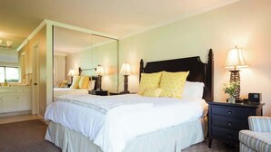 Een hotelkamer met een groot bed, bedlampjes, een nachtkastje, een stoel en een spiegel.