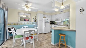 A modern kitchen with white cabinets, a central island, and a dining area with a white table and chairs. - Myrtle Beach Resort A 210 (Myrtle Beach)