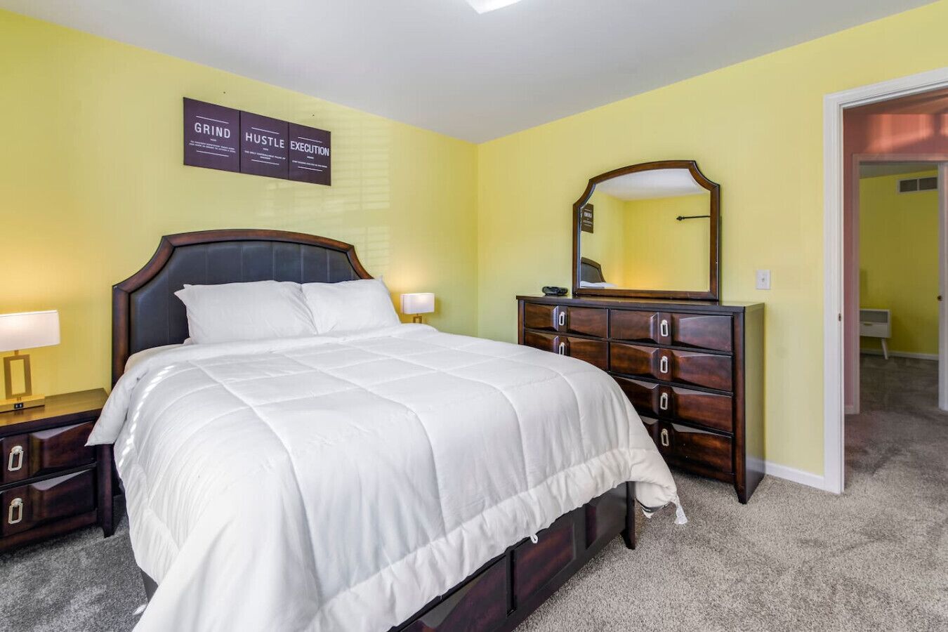 A bedroom with a bed, dresser, nightstands, and a mirror.
