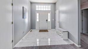 A hallway with a white door, a bench, and a light fixture on the ceiling. - Modern Comfort Loves Park Stylish 3BR Getaway (Loves Park)