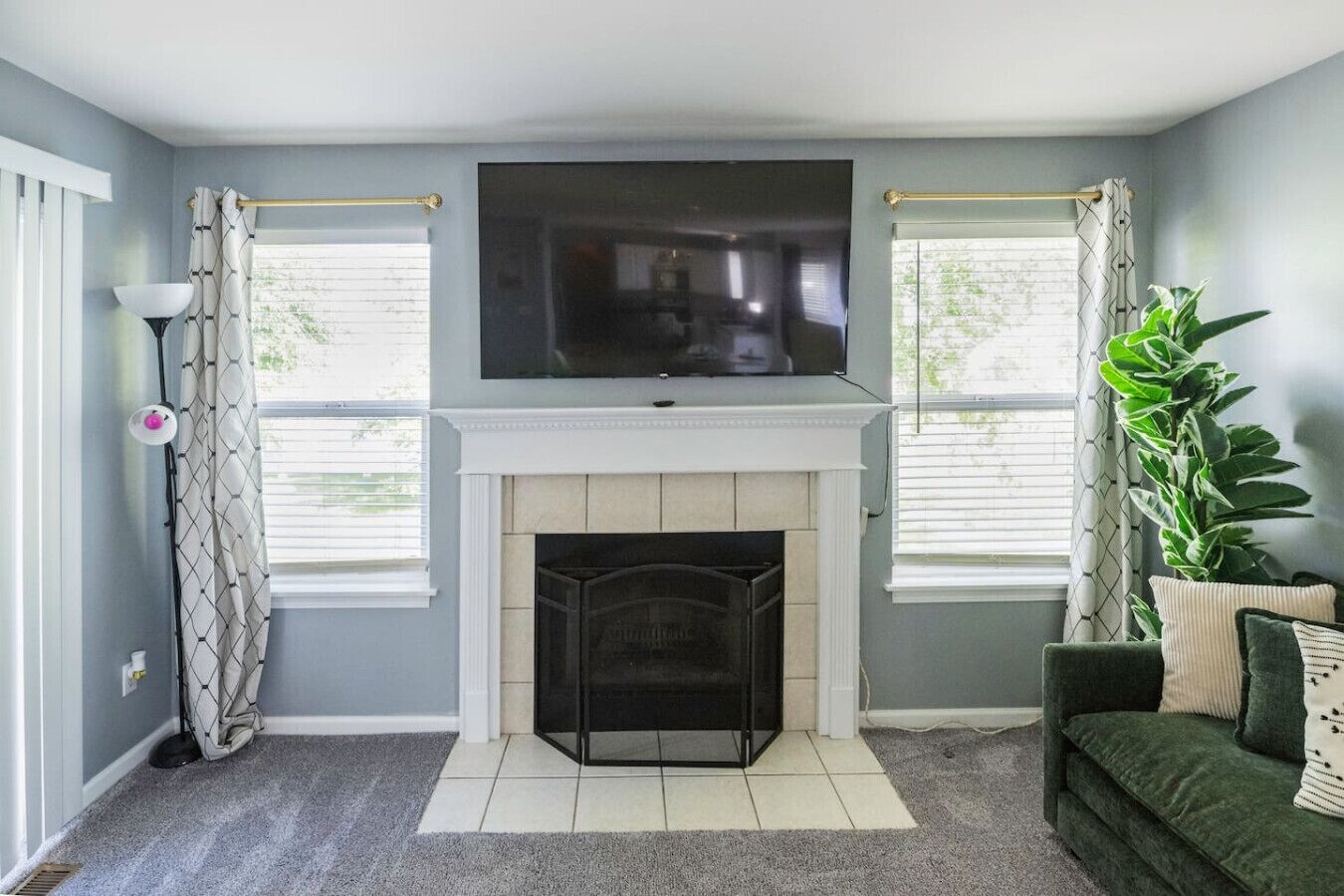 A living room with a fireplace, a flat-screen TV mounted above it, and a green sofa.
