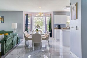 A modern dining area with a marble floor, a chandelier, and a view of the outdoors.