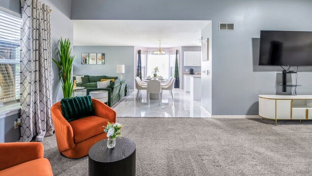 A modern living room with a sofa, coffee table, and TV. - Modern Comfort Loves Park Stylish 3BR Getaway (Loves Park)