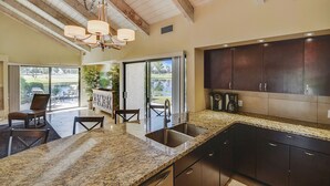 A kitchen with granite countertops, dark cabinets, and a chandelier. - Elegant Lakeside Villa (Rancho Mirage)
